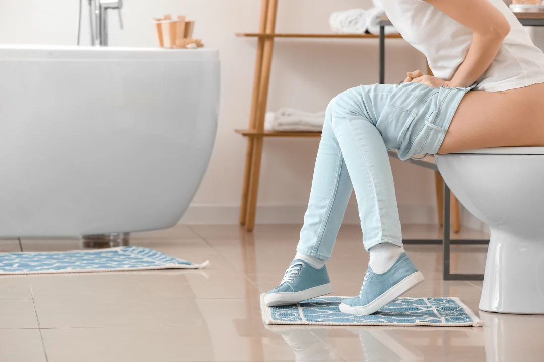 žena sedí na toaletě a je vidět, že jí nění dobře