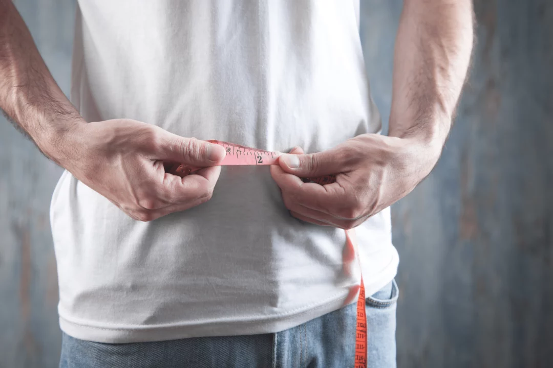 muž drží v ruce metr okolo pasu