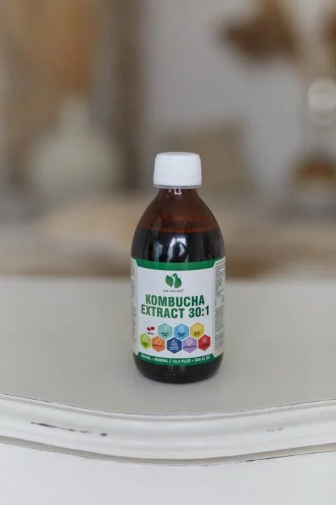 Láhev s extraktem kombuchy 30:1 na bílém stole, ideální pro zdraví a detoxikaci těla.