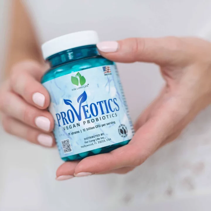 Osoba drží balení veganských probiotik Proveotics, obsahujících 12 miliard CFU na dávku.