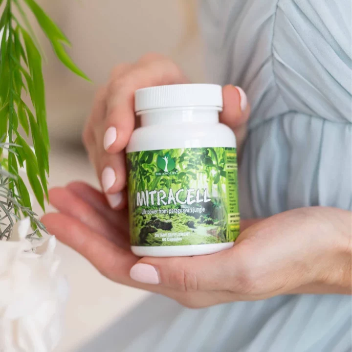 Osoba s jemně upravenými nehty drží láhev přírodního doplňku Mitracell s etiketou inspirovanou džunglí.