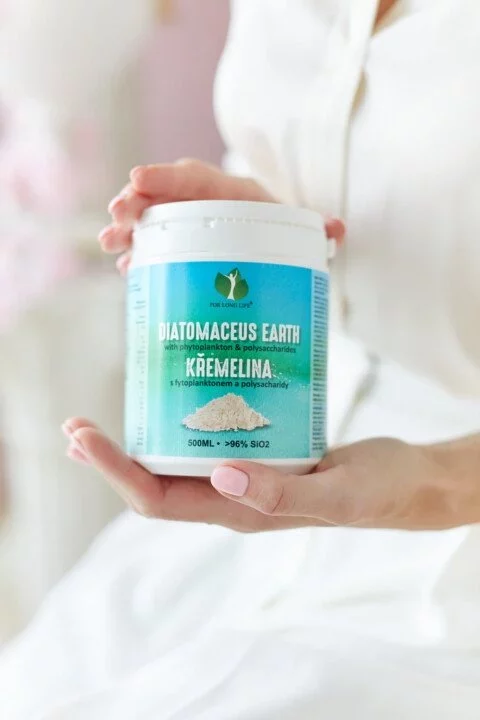 Ruce držící nádobu s křemelinou Diatomaceous Earth, přírodní doplněk pro zdraví a detoxikaci.