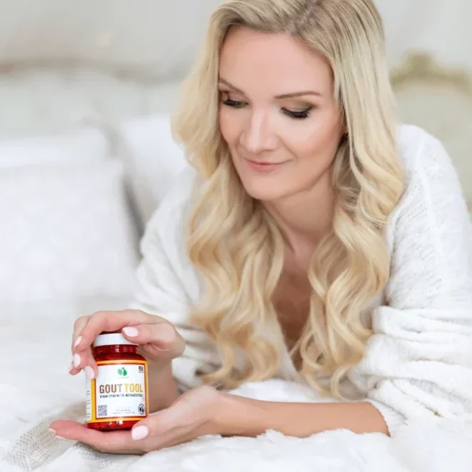 Žena držící láhev s doplňkem stravy Gout Tool v ložnici, záběr pro reklamu na zdraví a pohodu.