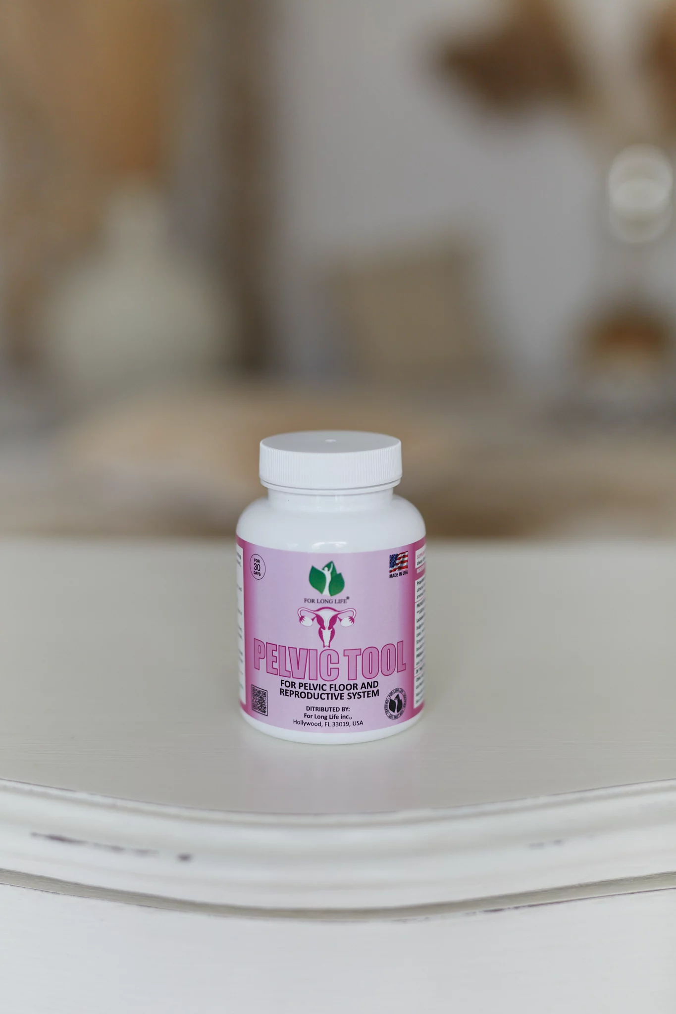 Láhev s označením „PelvicTool“ určená pro pánevní dno a reprodukční zdraví, postavená na lehkém dřevěném stole.